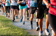 © coachwood - Legs of runners on a dirt path running a 5K race