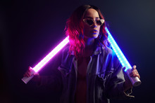 Portrait Of Young Girl In Glasses Holding Light Sticks In Red And Blue Neon In Studio