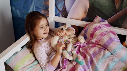 emotions and health: a happy girl lies in her white wooden bed at home. she smiles and laughs. a chi