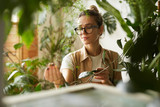 Fototapeta  - Young botanist in eyeglasses holding branch of decorative plant in her hand and examining it