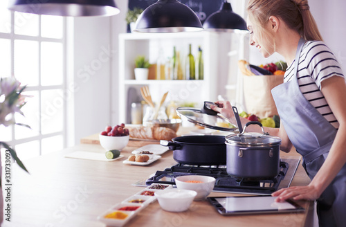 Young woman using a tablet computer to cook in her kitchen Tableau sur Toile