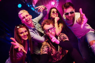 Going crazy and posing for the camera together. Young people is having fun in night club with colorful laser lights