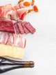 Meat plate with salami, bacon, hamon on light background. Meat composition with slices of meat products. Top view