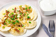 Homemade dumplings with toasted onions and bacon. Traditionally, the Ukrainian dish is decorated with green onions. Plate with dumplings on the table and sour cream.