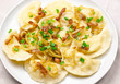 Homemade dumplings with toasted onions and bacon. Traditionally, the Ukrainian dish is decorated with green onions. Plate with dumplings on the table