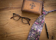 Floral neck tie with  glasses on a pine wood table with leather box, and other men's accessories for a fathers day