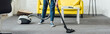 Cropped view of woman cleaning carpet with vacuum cleaner in living room, panoramic shot