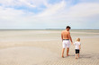 © Christin Lola - Father and His Young Child Walking on A White Sand Sandbar in the Ocean at a Public Beach
