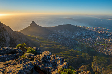 Wall Mural - Cityscape of Cape Town city and Lions head mountain peak at sunset with the Indian Ocean in the background as seen from the Table Mountain National Park, Western Cape Province, South Africa.