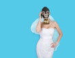 Bride in veil dress and protective mask in a gas mask posing on a delicate background