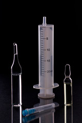 Wall Mural - Medical syringe and ampoules with medicine on a black background. Vaccination and virus protection concept