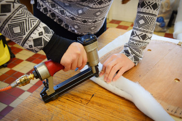 Wall Mural - Making new upholstery on old restored furniture. Making new chair seat. Woman work with pneumatic stapler in upholstery workshop. 