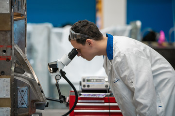 the engineer checks the correct setting of the metal mold for castings in the factory using a microscope