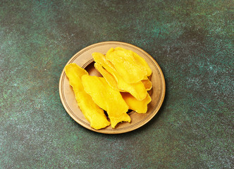 Poster - Dried mango fruit on green background. Yellow sliced mango. Top view.