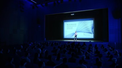 Wall Mural - On-Stage Speaker Greets Audience, Presents Technology Product, Uses Remote Control for Presentation, Showing Infographics, Statistics Animation on Big Screen. Live Event / Start-up Conference