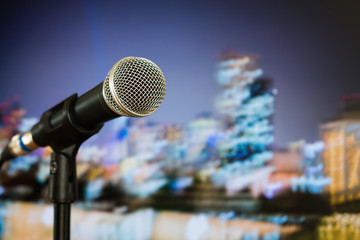 Microphone for speaker on speech in seminar room or speaking conference hall at public stage on podium convention event in light background. Comunication equipment meeting center concept