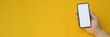 © bongkarn - Cropped shot of a man holding blank screen smartphone on yellow background