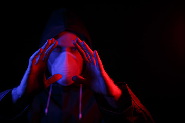 Wall Mural - A man in a protective rubber suit and a white medical mask. Virus protection. Illuminated in red and blue.