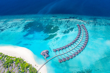 Perfect aerial landscape, luxury tropical resort or hotel with water villas and beautiful beach scenery. Amazing bird eyes view in Maldives, landscape seascape aerial view over a Maldives