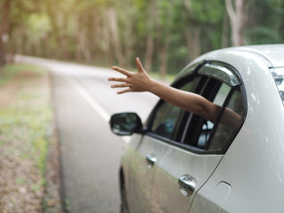 asian woman show her hand out from the window car and feeling the wind through his hand. use for travel concept.