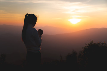 Wall Mural - Silhouette of young  human hands  praying to god  at sunrise, Christian Religion concept background.