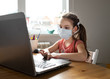 © Olga - Caucasian preteen girl with medical mask concentrated on her task with laptop. Concept of distance learning in isolation while coronavirus