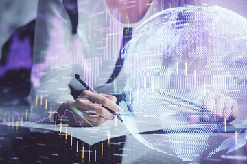 Double exposure of hands making notes with forex chart huds. Stock market concept.