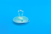 Light Blue Baby Pacifier Lies On A Blue Background, Object Baby Accessories With A Copy Space.