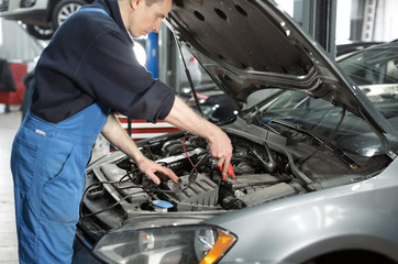 Mechanic examining under hood of car at the repair garage Car service mechanic repairing and maintenance Car. auto mechanic man or smith with wrench at workshop