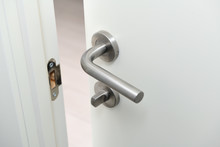 Detail Of A Metallic Knob On White Door Horizontal.Stainless Steel Handle On A White Wooden Door.The Door Is Open.
