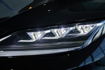 Luminous headlight on a new car in the showroom