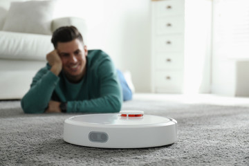 Sticker - Man resting while robotic vacuum cleaner doing his work at home