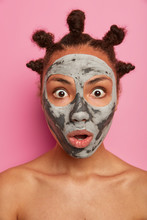 Emotional Shocked Afro American Woman Wears Mask For Face, Reduces Wrinkles On Complexion, Stands Naked, Has Well Cared Healthy Skin, Reacts On Something Surprising, Isolated Over Pink Background