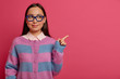 Beautiful clever female student in big glasses and jumper, introduces product promo, recommends click on link, shows item on pink background, presents new app for studying, shows best price.