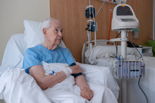 Elderly Man In A Hospital Bed Undergoing A Blood Pressure Test