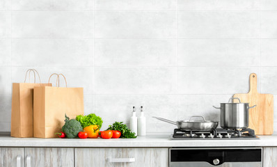 Contemporary kitchen front view, fresh vegetables just bought in a supermarket and put on a kitchen countertop, ready for cooking