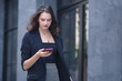 © eakgrungenerd - businesswomen using smartphone walking outside office in relax time.