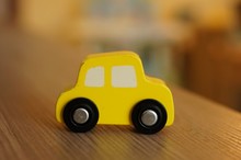 Closeup Shot Of A Yellow Wooden Toy Car On A Wooden Surface