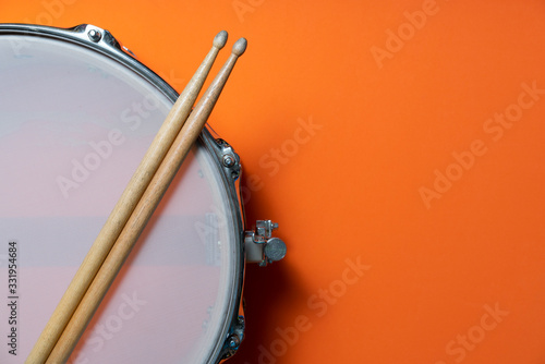 Cuadros en Lienzo Drum stick and drum on orange table background, top view, music concept