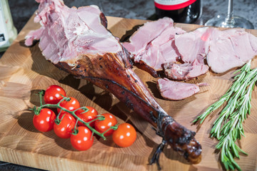 Wall Mural - Smoked lamb leg on a wooden board with a knife