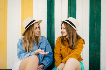 Two friends chatting calmly about their things, lies resting in some beach huts on a very colorful afternoon