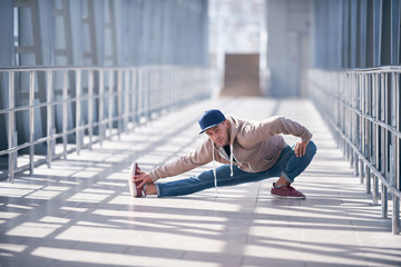 Young man practices yoga asana indoors in the empty covered footbridge