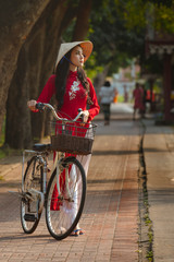 Portrait of Vietnamese girl traditional red dress,Beautiful young asian woman wearing Vietnam with bicycle