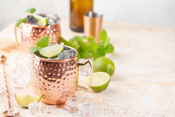 Wall Mural - Cold Moscow Mules cocktail with ginger beer, vodka, lime. White stone background.