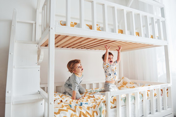 Two little boys resting and have fun indoors in the bedroom together