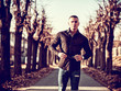 © theartofphoto - One handsome young man in urban setting in European city walking along street with trees, wearing black jacket and jeans
