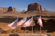 US Flags blowing in wind in front of red buttes and colorful spires of Monument Valley Navajo Tribal Park, Southern Utah near Arizona border