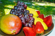Tropical Fruits As Banana Mango Strawberries Black Grapes  In A Brown Plate Garden Picture Image Background