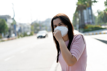 Close up of a woman in a suit wearing Protective face mask and cough, get ready for Coronavirus and pm 2.5 fighting against beside road in background.