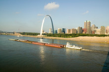 Daytime View Of Tug Boat Pushing Barge Down Mississippi  River In Front Of Gateway Arch And Skyline Of St. Louis, Missouri As Seen From East St. Louis, Illinois On The Mississippi River